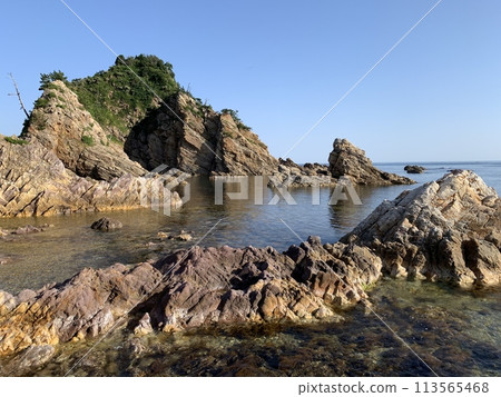 A rocky coastline seen under clear skies A rocky coastline seen under clear skies 113565468