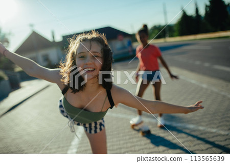 Teenager girl best friends with skateboards spending time outdoors in city during warm summer holiday day. Teenager girl best friends with skateboards spending time outdoors in city during warm summer holiday day. 113565639