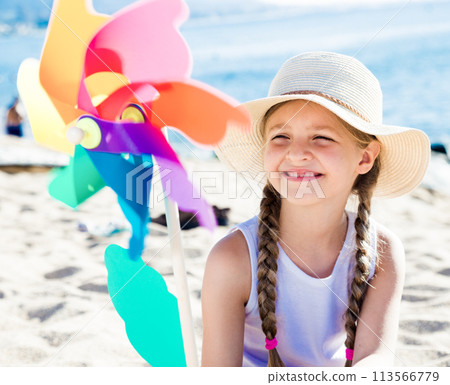 Girl with windmill on sea in summer 113566779