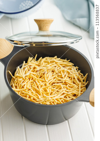 Uncooked spaetzle pasta in pot on kitchen table. 113568837