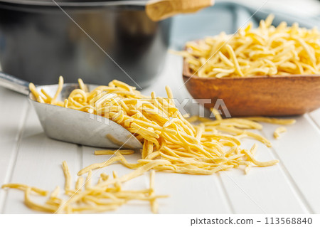 Uncooked spaetzle pasta in scoop on kitchen table. 113568840