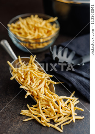 Uncooked spaetzle pasta in scoop on kitchen table. 113568841