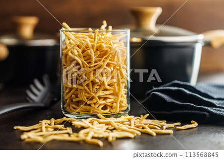 Uncooked spaetzle pasta in jar on kitchen table. 113568845