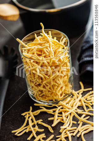 Uncooked spaetzle pasta in jar on kitchen table. Uncooked spaetzle pasta in jar on kitchen table. 113568846