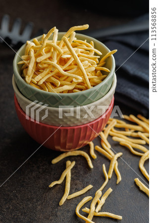 Uncooked spaetzle pasta in bowl on kitchen table. Uncooked spaetzle pasta in bowl on kitchen table. 113568856