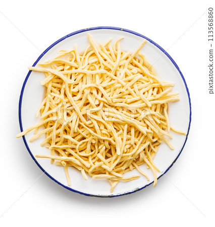 Uncooked spaetzle pasta on plate isolated on white background. Uncooked spaetzle pasta on plate isolated on white background. 113568860
