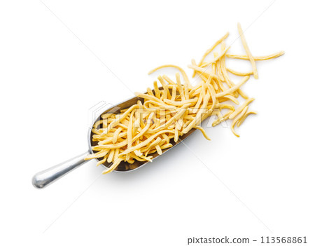 Uncooked spaetzle pasta in scoop isolated on white background. Uncooked spaetzle pasta in scoop isolated on white background. 113568861