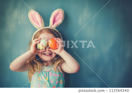 cute little girl with bunny ears holds Easter eggs by the eyes, Easter holiday card with copy space cute little girl with bunny ears holds Easter eggs by the eyes, Easter holiday card with copy space 113569340