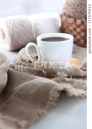 A cup of coffee on a background of multicolored yarn for hand knitting. Handmade work. The concept of a hobby. Vertical photo. A cup of coffee on a background of multicolored yarn for hand knitting. Handmade work. The concept of a hobby. Vertical photo. 113570413