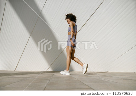 Young woman in tracksuit have rest after workout outside crossing on building background 113570623