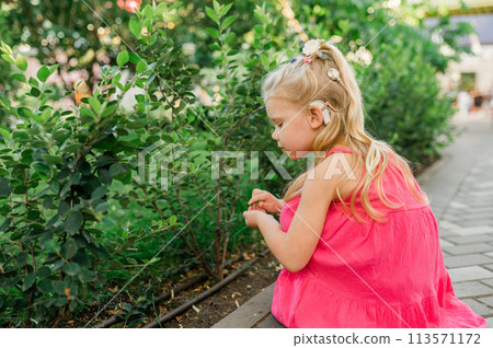 Child walks with cochlear implant hearing aid in summer street. Inclusion and modern technologies for treating hearing loss. Copy space 113571172