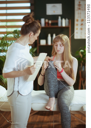 therapist woman listening to clients complaint of leg pain 113571498