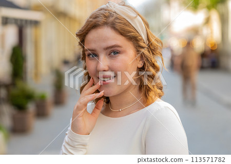 Happy redhead woman smiling looking away dreaming resting good news feel satisfied in city street 113571782