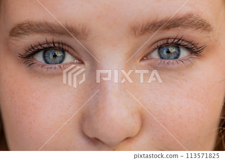 Extreme close-up macro portrait of young smiling redhead face, pretty woman's eyes looking at camera 113571825