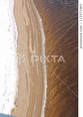 nature in winter on the banks of the Volga, ice with sand and snow, river sandy background. nature in winter on the banks of the Volga, ice with sand and snow, river sandy background. 113571965