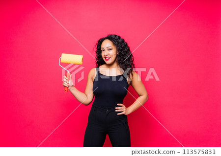 Happy young African woman with paintroller, toothy smile during home renovation Happy young African woman with paintroller, toothy smile during home renovation 113575831