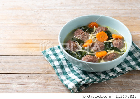 Italian Wedding Soup with meatballs and spinach on wooden table Italian Wedding Soup with meatballs and spinach on wooden table 113576823