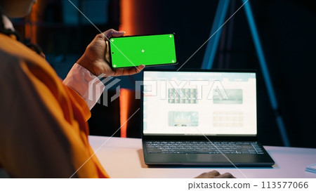 Business student looks at greenscreen on phone app and learning to use tax service software, money management. Young woman holding device with isolated mockup display, e learning. Camera A. 113577066