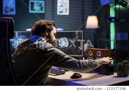 Software technician inserting disk in computer with rogue superintelligence AI to use it for evil plan. IT specialist putting cartridge containing virus infected artificial intelligence bot in PC 113577196