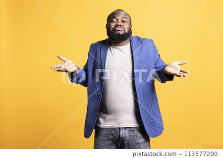 African american man shrugging shoulders, not caring, having detached apathy facial expression. Apathetic BIPOC person doing disinterest indifferent hand gesturing, studio background African american man shrugging shoulders, not caring, having detached apathy facial expression. Apathetic BIPOC person doing disinterest indifferent hand gesturing, studio background 113577200