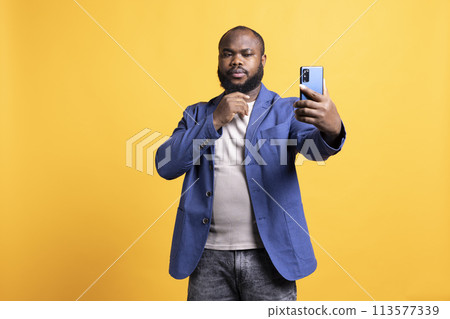 Narcissistic man using cellphone to take selfies, stroking his chin. Vain social media user taking photos using phone selfie camera, isolated over yellow studio background Narcissistic man using cellphone to take selfies, stroking his chin. Vain social media user taking photos using phone selfie camera, isolated over yellow studio background 113577339