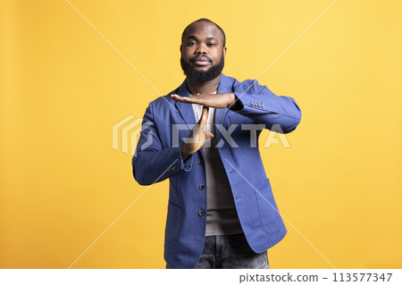 Portrait of assertive man asking for timeout, doing hand gestures, feeling fatigued. Unhappy person doing vehement pause sign gesturing, wishing for break, studio background 113577347