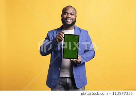 Smiling african american man presenting tablet with green screen display, isolated over studio background. Cheerful BIPOC person creating promotion with blank copy space mockup device Smiling african american man presenting tablet with green screen display, isolated over studio background. Cheerful BIPOC person creating promotion with blank copy space mockup device 113577355