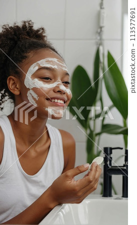 Happy young beautiful African American woman taking care of her facial skin. 113577691