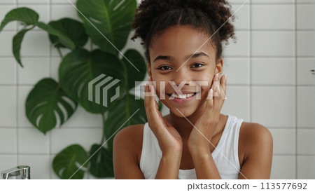 Happy young beautiful African American woman taking care of her facial skin. 113577692