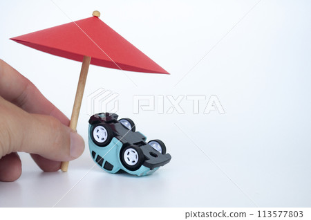Red toy umbrella and upside down car on white background. Insurance coverage concept Red toy umbrella and upside down car on white background. Insurance coverage concept 113577803