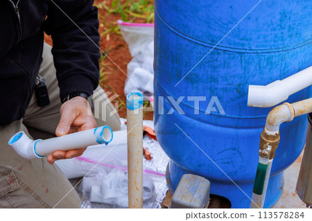 Plumber connects underground pipeline for new house to well pump Plumber connects underground pipeline for new house to well pump 113578284