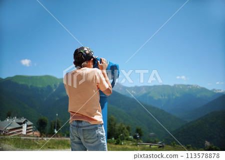 boy observing mountains panorama through stationary binoculars 113578878