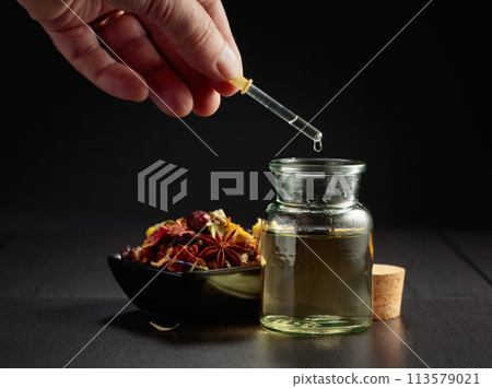 Dropping essential oil or herbal tincture into a small bottle. Dropping essential oil or herbal tincture into a small bottle. 113579021