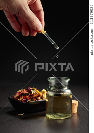 Dropping essential oil or herbal tincture into a small bottle. 113579022