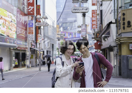 Inbound: A foreign couple sightseeing in Shibuya while looking at their smartphones Inbound: A foreign couple sightseeing in Shibuya while looking at their smartphones 113579781