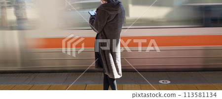冬天在車站等火車的年輕女子和經過的火車 113581134