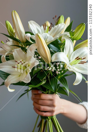 A woman holds a bountiful bouquet of pure white lilies A woman holds a bountiful bouquet of pure white lilies 113582140