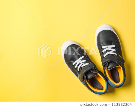 Gray and yellow sneakers on yellow background 113582304