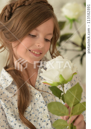 Pretty little girl smiling and posing with flowers 113582891