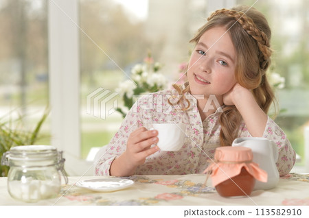 Smiling little girl holding big cup of tea 113582910