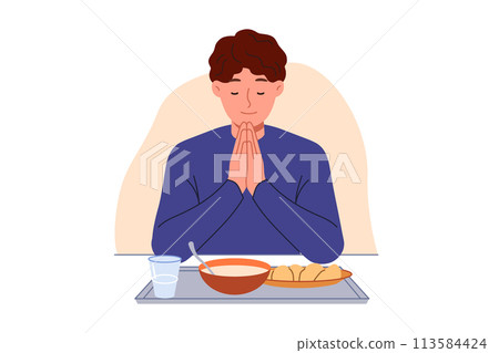 Man prays sitting at table with food, observing christian tradition and expressing gratitude to god Man prays sitting at table with food, observing christian tradition and expressing gratitude to god 113584424