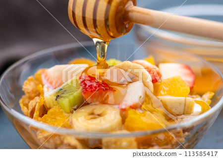 在早餐優格麥片上撒上蜂蜜,上面撒上水果 在早餐優格麥片上撒上蜂蜜,上面撒上水果 113585417