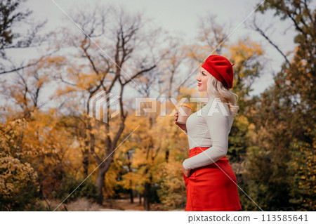 A woman in a red hat and red skirt is standing in a forest with a cup in her hand. 113585641