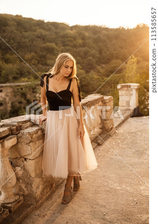 Blonde long hair, nature summer happy adult girl with long blond hair developing in the wind in nature. Dressed in a black top, white skirt. Blonde long hair, nature summer happy adult girl with long blond hair developing in the wind in nature. Dressed in a black top, white skirt. 113585657