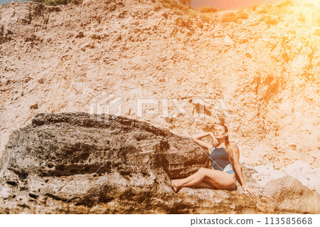 Woman travel summer sea. A happy tourist in a blue bikini enjoying the scenic view of the sea and volcanic mountains while taking pictures to capture the memories of her travel adventure. 113585668