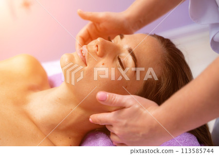 Relaxing massage. European woman getting facial massage in spa salon, side view 113585744