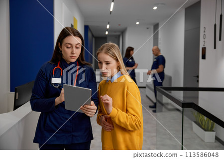 Patient and doctor talking discussing something looking at digital tablet Patient and doctor talking discussing something looking at digital tablet 113586048
