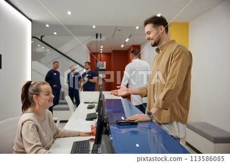 Man visitor talking and smiling to nurse at reception in clinic waiting room 113586085