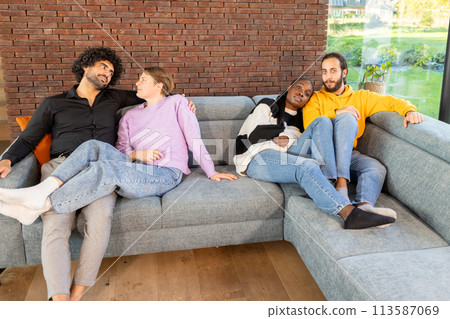 Relaxed Friends Enjoying a Comfortable Sofa in a Cozy Room Relaxed Friends Enjoying a Comfortable Sofa in a Cozy Room 113587069