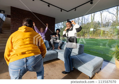 Joyful Friends Dancing Together in a Bright Modern Living Room 113587070
